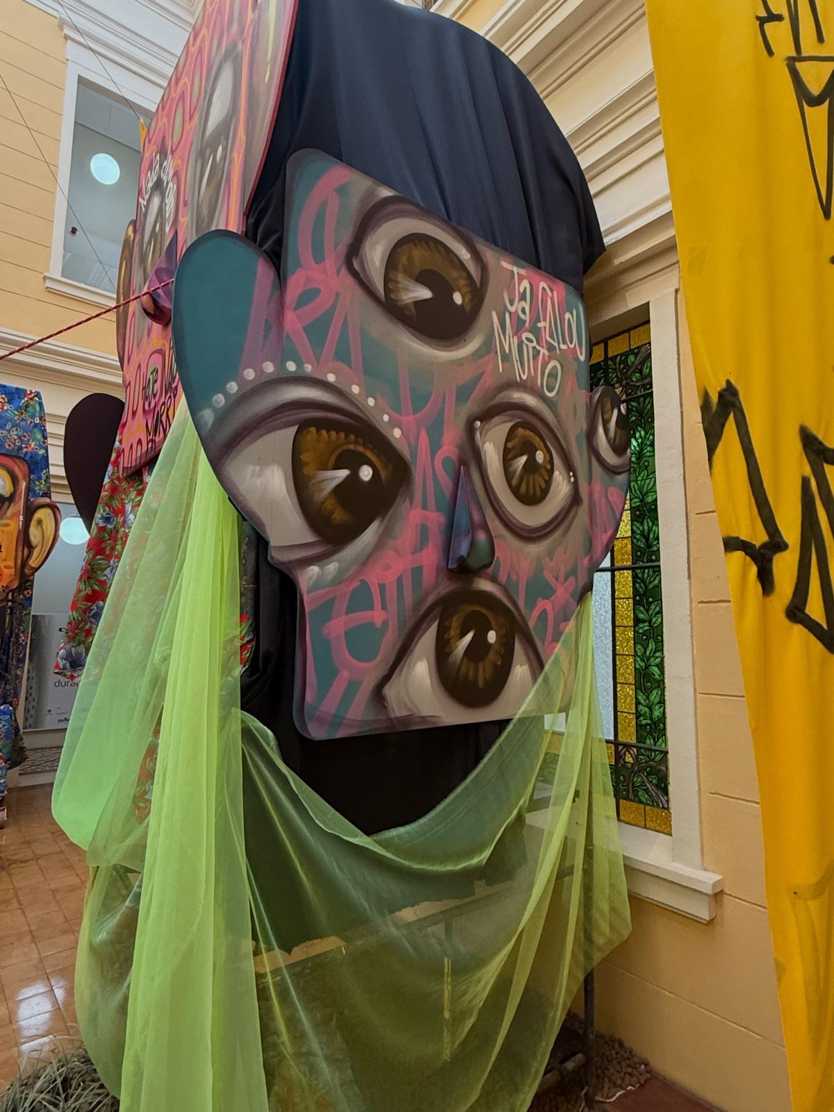 Escultura de rosto com véu verde na exposição A Casa