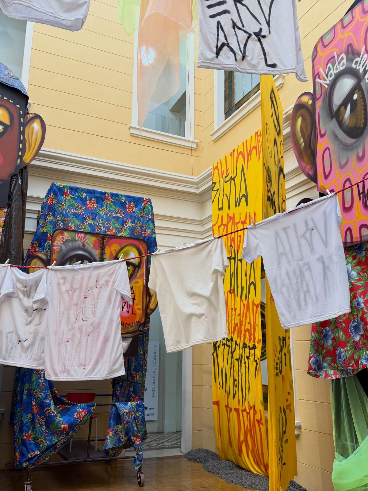 Instalação da exposição A Casa com varais de roupas e rostos pintados