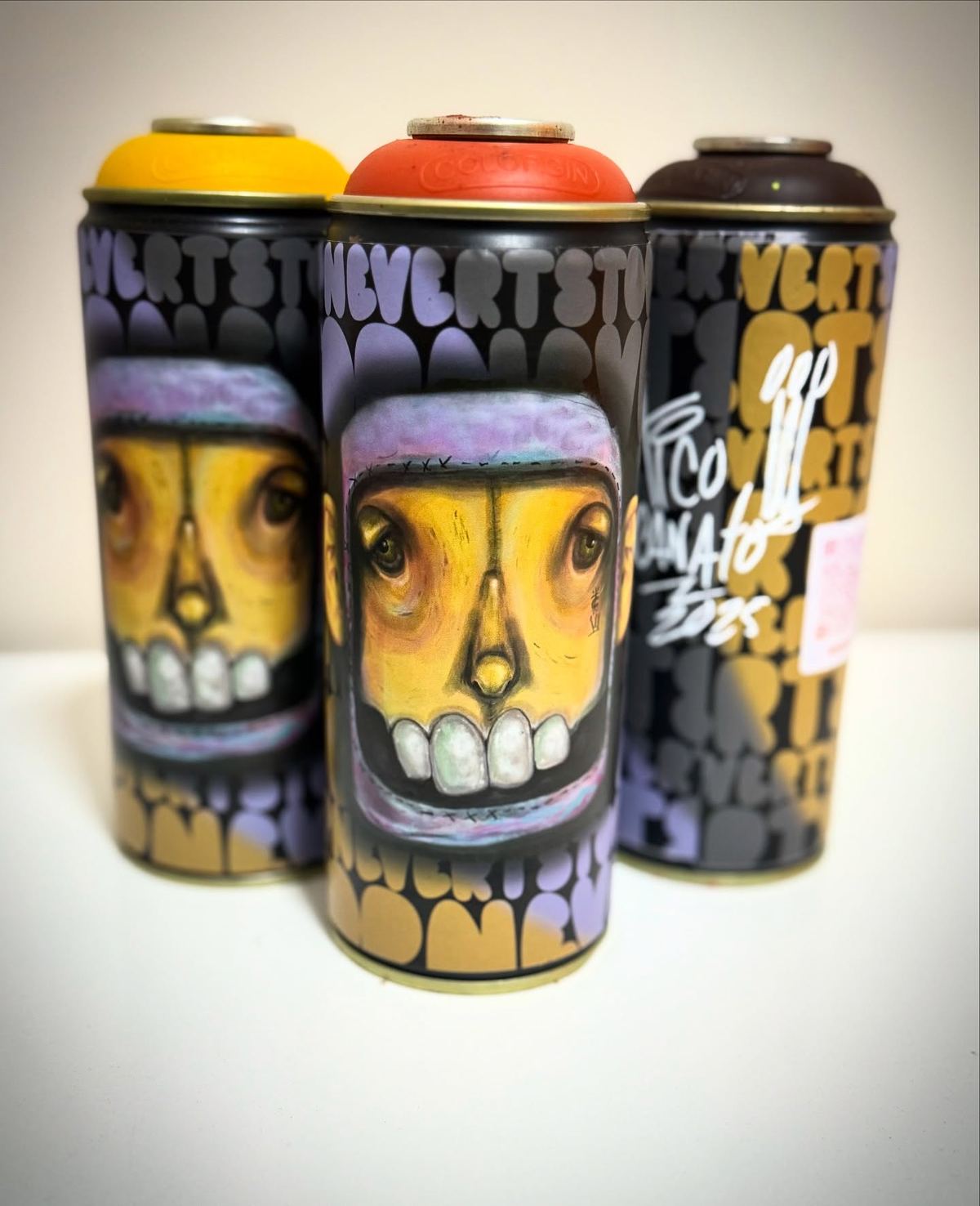 Três latas de spray customizadas com o rosto do Ondi