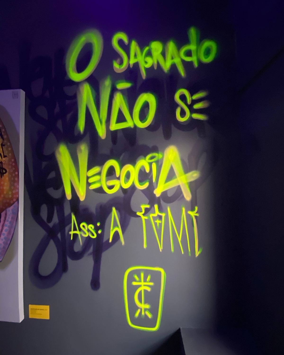 Frase O sagrado não se negocia escrita em neon verde na exposição O Sagrado